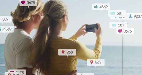 Couple on Beach Capturing Moments with Social Media Overlay
