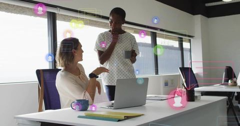 Coworkers collaborating over laptop in sunlit modern office with floating ui overlays