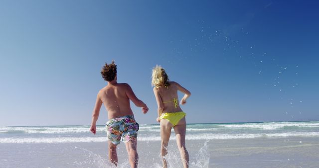 Joyful couple running into ocean on a bright sunny beach - Download Free Stock Images Pikwizard.com