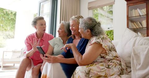 Senior Friends Sharing Technology Moment Together on Sofa