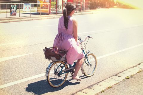 Woman Cycling in Sunlight on City Street