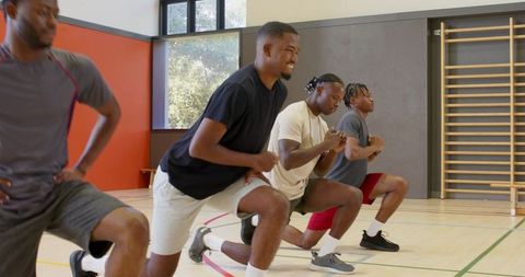 African american men doing lunges in indoor gym during team warmup and cardio training