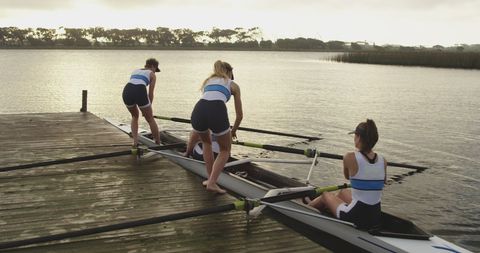 Women Athletes Preparing Rowing Boat at Lakeside Dawn - Download Free Stock Images Pikwizard.com