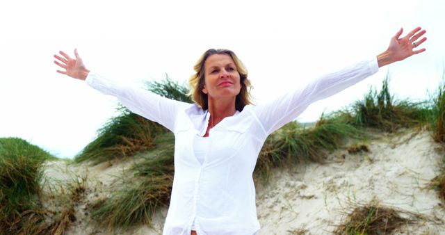 Joyful Mature Woman with Arms Outstretched on Beach Dune - Download Free Stock Images Pikwizard.com