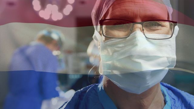 Caucasian senior female doctor wears face mask and surgical cap with Russian flag overlay. She stands confidently in a hospital, with blurred surgical team in background. Ideal for use in articles about national healthcare system, medical professionals, and resilience in healthcare.