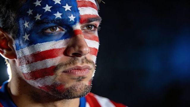Gazing man with american flag face paint in dramatic rim-lit close-up portrait patriotic