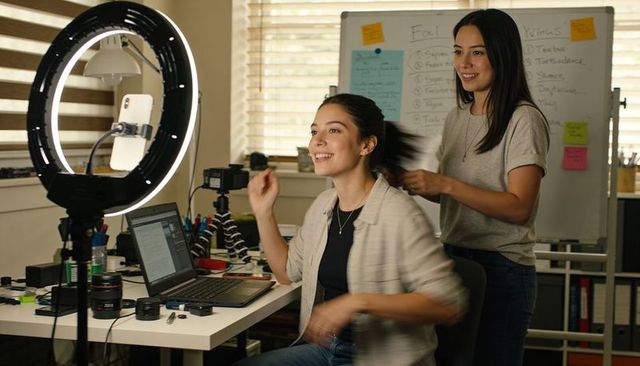 Smiling creator preparing to record with ring light in home studio workspace