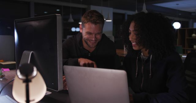 Young Professionals Smiling at Computer in Dimly Lit Office - Download Free Stock Images Pikwizard.com