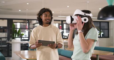 African American coworkers testing VR headset with tablet in modern open-plan office