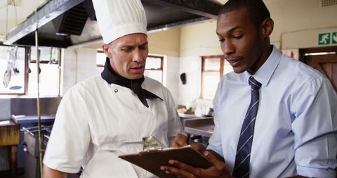 Manager and chef discussing details in commercial kitchen
