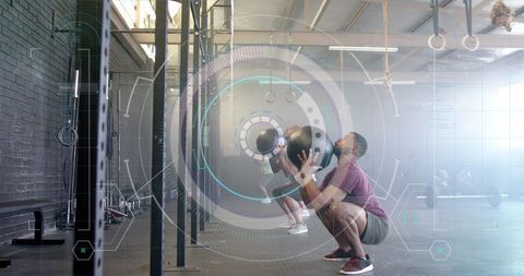 Men Engaged in CrossFit with Medicine Balls Focused on Digital Fitness Technology