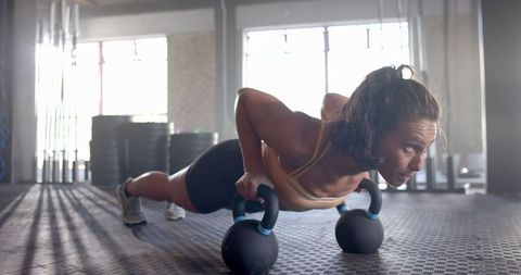 Woman Performing Push-Ups with Kettlebells in Gym for Strength Training - Download Free Stock Images Pikwizard.com