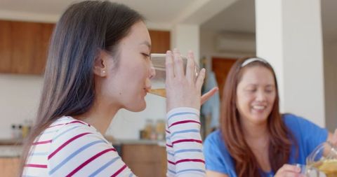 Mother and daughter enjoying refreshing juice at kitchen counter