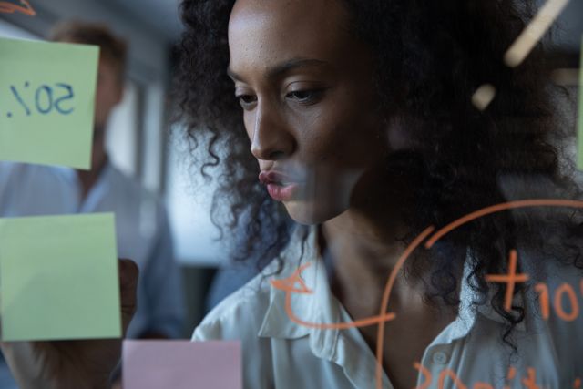 Focused Biracial Businesswoman Writing on Glass Board in Modern Office - Download Free Stock Images Pikwizard.com