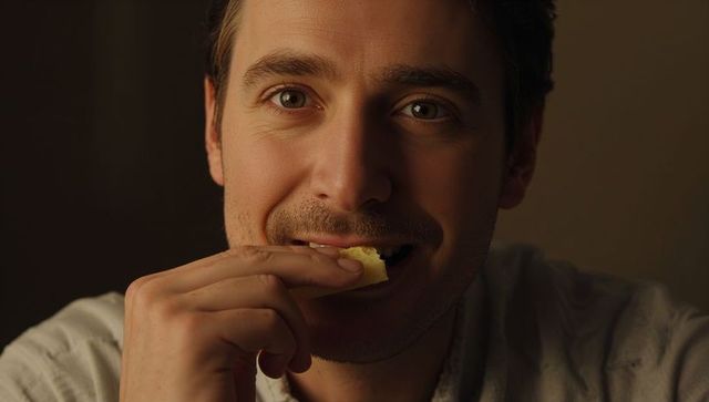 Smiling man eating cracker making eye contact warm closeup portrait