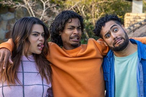 Diverse friends making exaggerated faces while hugging and joking in sunny backyard