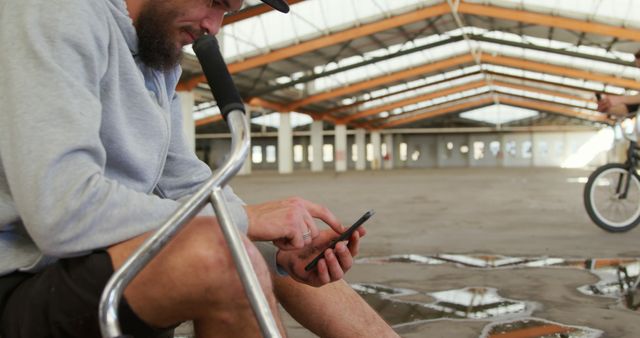 BMX Rider Taking Break in Abandoned Warehouse, Using Smartphone - Download Free Stock Images Pikwizard.com