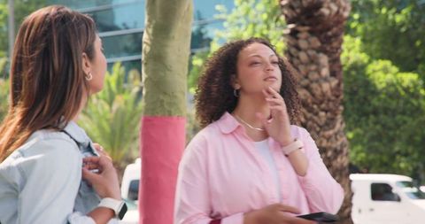 African american women chatting on urban sidewalk with phone near palm trees city lifestyle