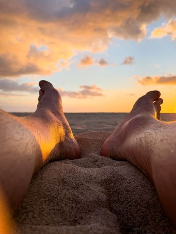 Relaxed Sunset on Sandy Beach with Bare Feet in Foreground