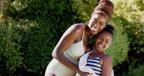 Mother hugging daughter outdoors celebrating family time