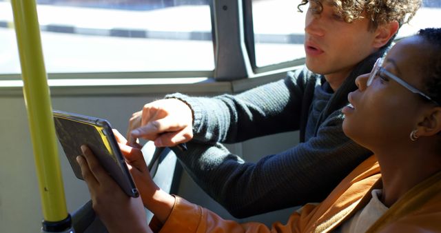 Diverse couple sitting in city bus using tablet - Download Free Stock Photos Pikwizard.com