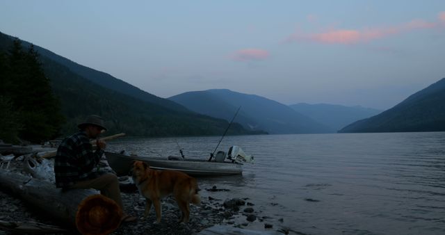 Man playing flute by peaceful lakeside with dog at sunset - Download Free Stock Images Pikwizard.com
