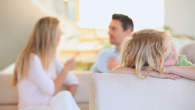 Young boy appears visibly sad while his parents argue in the background in their living room. The boy is resting his head on his arms, clearly impacted by the family tension. The parents in the background appear out of focus, highlighting the child's emotional state. This video captures family conflict and emotional challenges faced by children during parental disputes. It can be used in articles, blogs, and resources on parenting, family counseling, emotional well-being, and domestic issues.