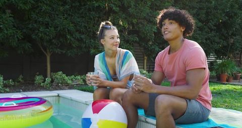 Diverse couple enjoying summer by home pool in relaxing atmosphere