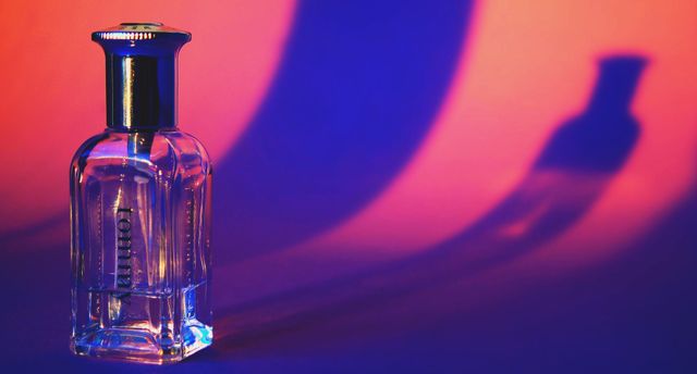 Elegant perfume bottle with striking colorful background lighting perfect for advertising campaigns, beauty and fashion publications, or decor. Ideal for highlighting luxury products, fragrances, and cosmetics.