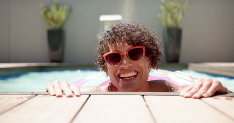 Smiling Man Relaxing in Swimming Pool on Sunny Day