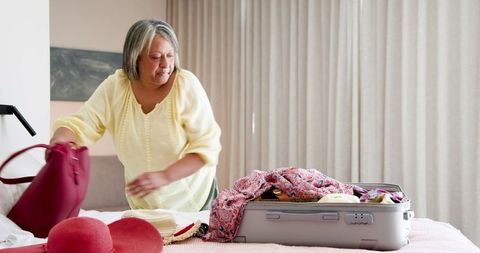 Senior Woman Packing Clothes for Vacation in Bedroom