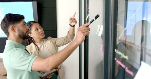 Colleagues Brainstorming on Glass Board in Modern Office