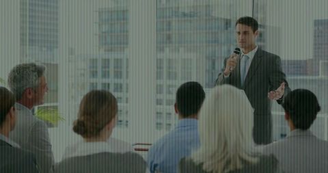 Executive presenting to corporate audience in modern boardroom with city skyline backdrop