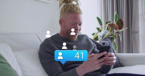 Surprised man reacting to 41 new followers on smartphone while relaxing on sofa