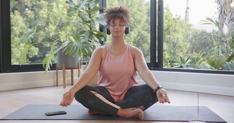 Calm African American Woman Meditating with Headphones at Home