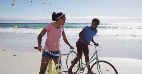 Friends Enjoying Beach Adventure While Pushing Bicycles