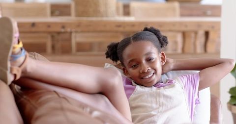 Smiling Girl Relaxing on Leather Sofa in Cozy Living Room