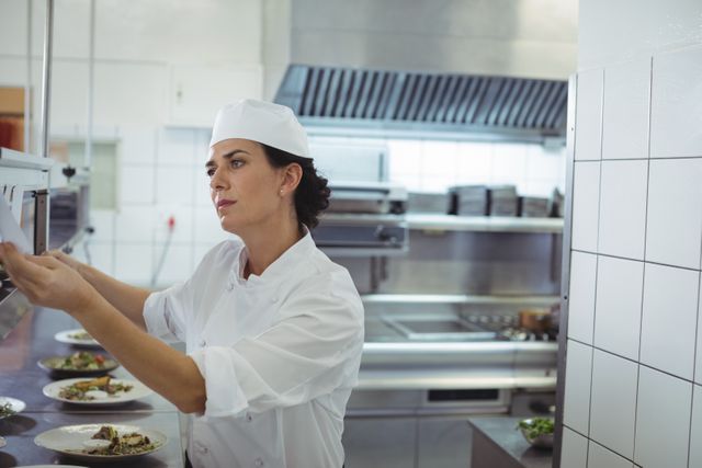 Female chef looking at an order list in the commercial kitchen at restaurant