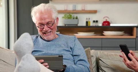 Happy senior couple relaxing at home using modern technology