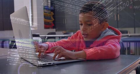 Young boy coding and typing on laptop in classroom learning technology