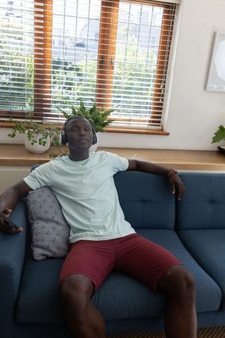 Young Man Relaxing on Sofa with Headphones in Modern Living Room