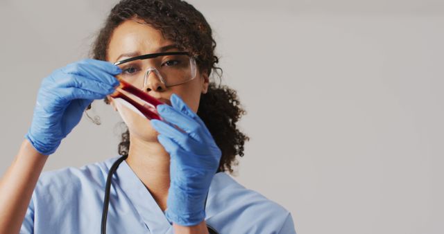 Female scientist wearing safety gear meticulously analyzing a blood sample. Ideal for use in healthcare, medical research, scientific publications, and educational materials. Perfect for presenting medical analysis, laboratory procedures, and the importance of safety in healthcare settings.