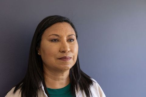 Serene mature woman headshot in teal top and light jacket, three-quarter closeup