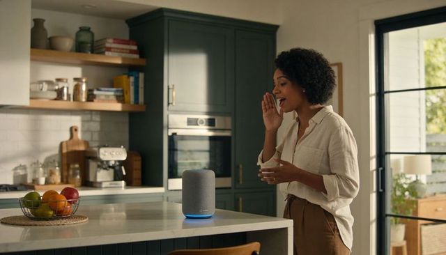 Woman talking to smart speaker on kitchen island morning routine voice assistant