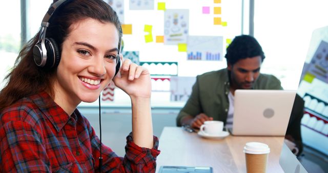 Smiling Woman Using Headphones at Modern Office Workstation - Download Free Stock Images Pikwizard.com