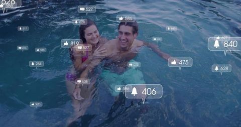 Smiling couple floating in ocean wearing swimwear with social media like overlays