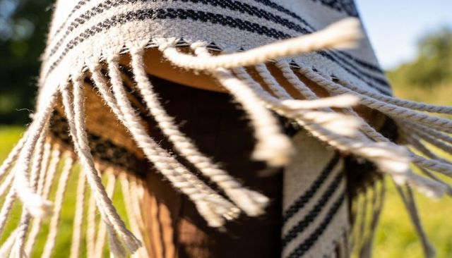 Wool fringe fluttering over brown garment in sunny meadow closeup textile texture