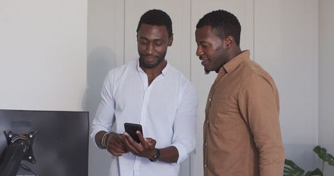 Friends Sharing Laughter While Looking at Smartphone Indoors