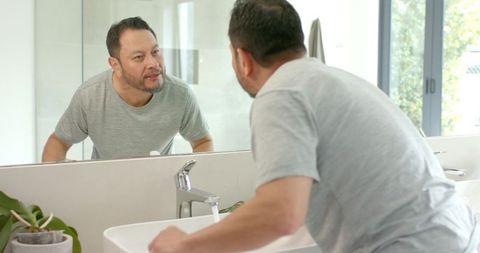 Man Examining Reflection in Modern Bathroom Mirror for Personal Care