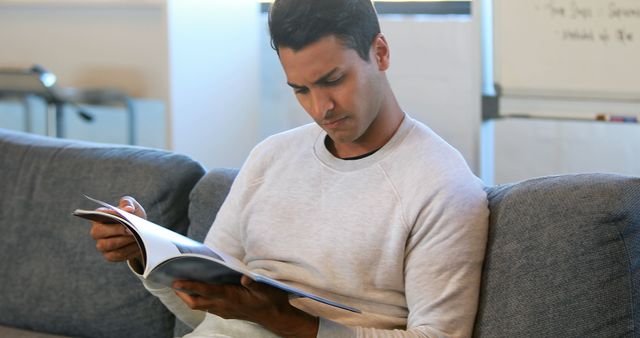 Man reading a magazine in a waiting room sitting on a couch